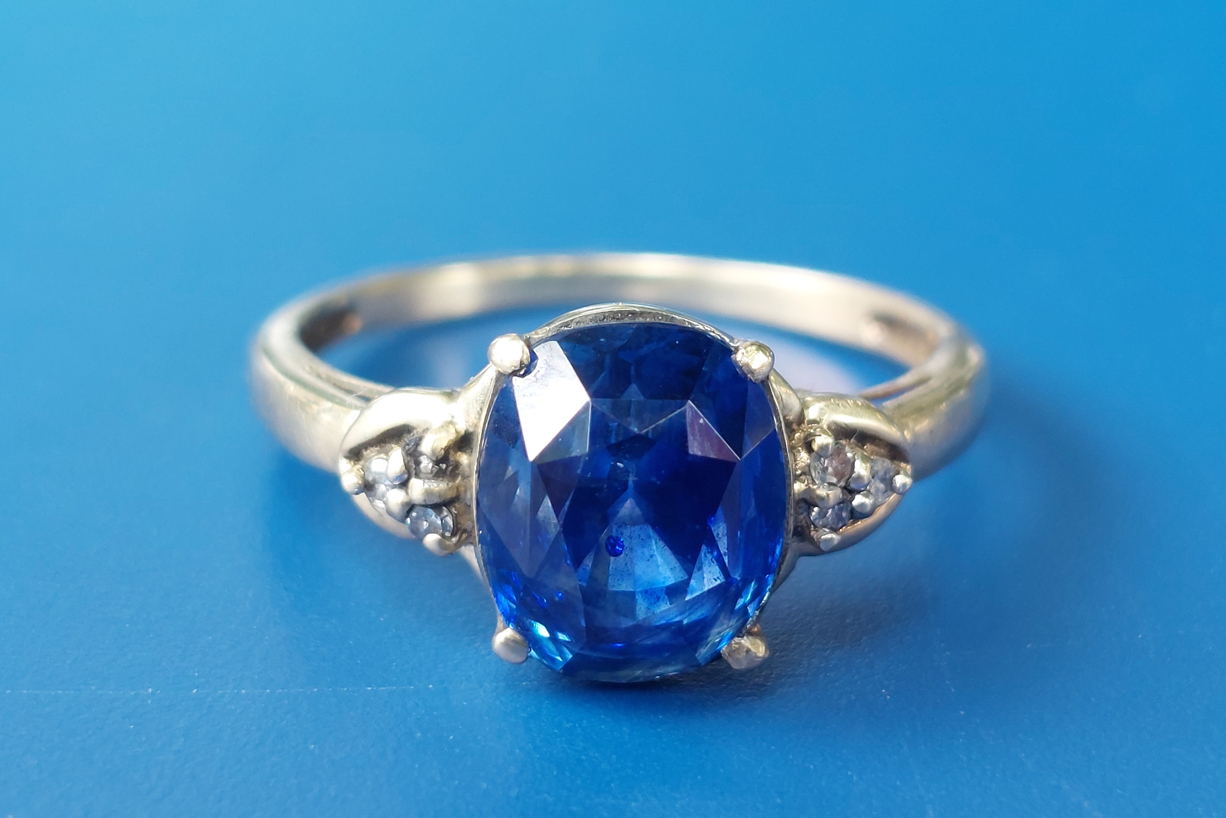 4 carat deep cornflower blue example has three small diamonds to each shoulder